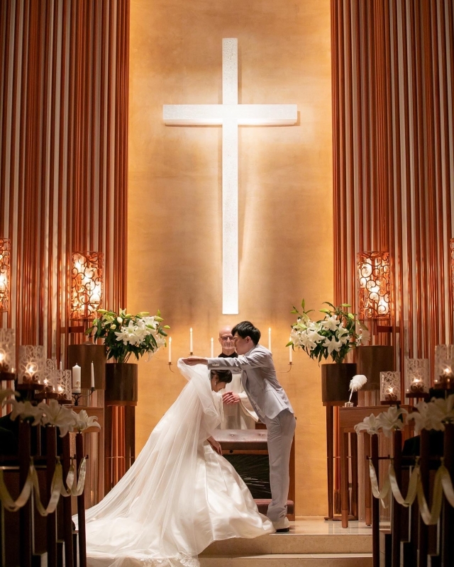大きな十字架が印象的な祭壇でベールダウンをする新郎新婦