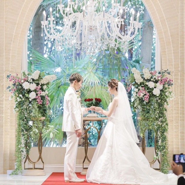 植物がたくさん飾られた祭壇の前に立つ新郎新婦