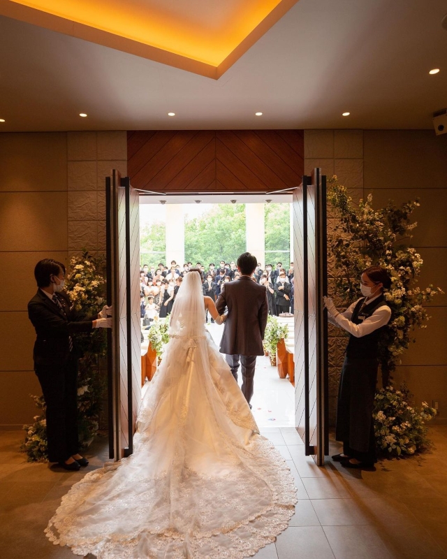 両脇に花を飾ったチャペルの扉から出ていく新郎新婦