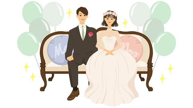 風船で飾られたソファに座っている新郎新婦