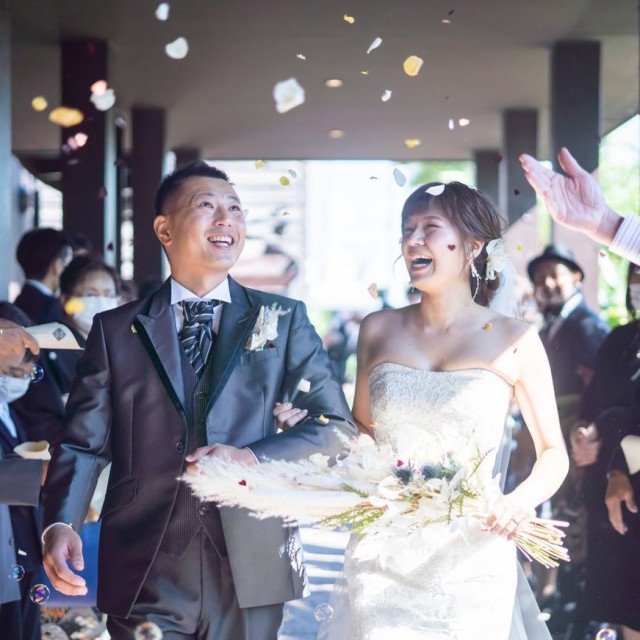 色とりどりの花びらが舞う中で笑いあう新郎新婦
