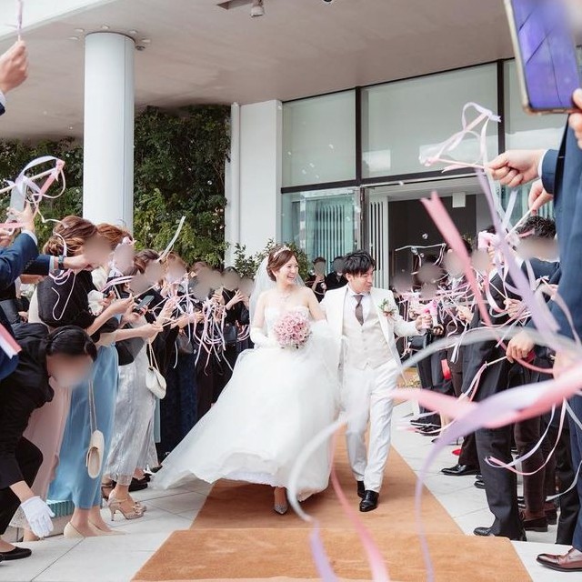 退場する新郎新婦に向けてリボンを振るゲストたち