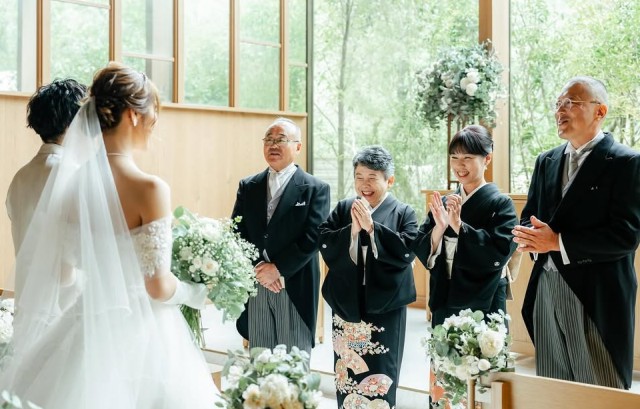 新郎新婦の姿を見て拍手をする両家の親