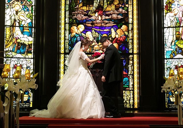 新婦が1本のバラを新郎の胸ポケットにさす様子