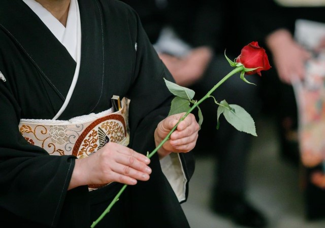 黒留袖を着た女性ゲストがダーズンローズ演出で使うバラを持つ様子