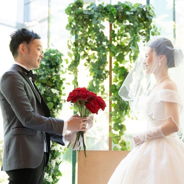 新郎が花嫁に12本のバラの花束を渡している様子
