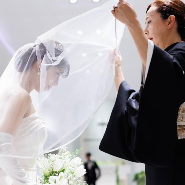 娘のウェディングベールを下す母親