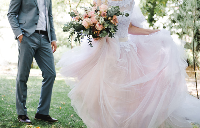 ウェディングドレスのトレーンを持ちながら歩く花嫁