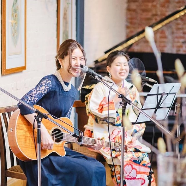 ギターを弾いて歌う女性2人