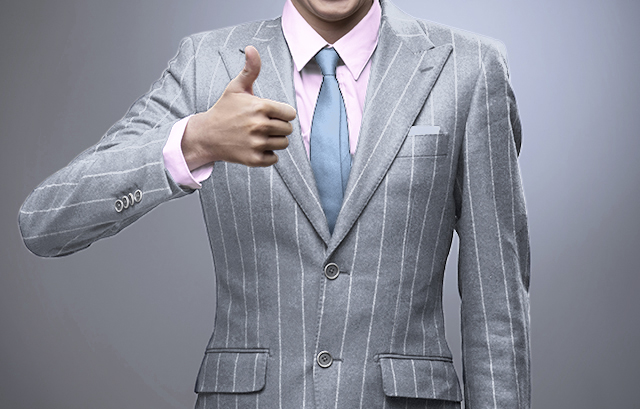 ライトグレーのスーツにピンクのシャツとライトブルーのネクタイを合わせる男性