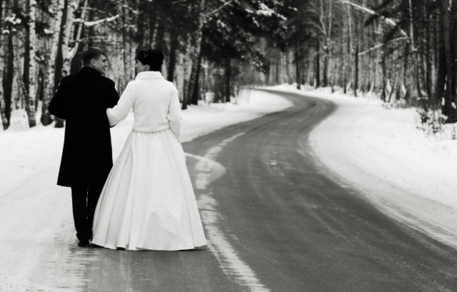 雪が積もる道路を歩く新郎新婦の白黒写真