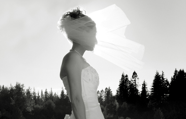太陽をバックに花嫁のベールがなびく瞬間の白黒写真