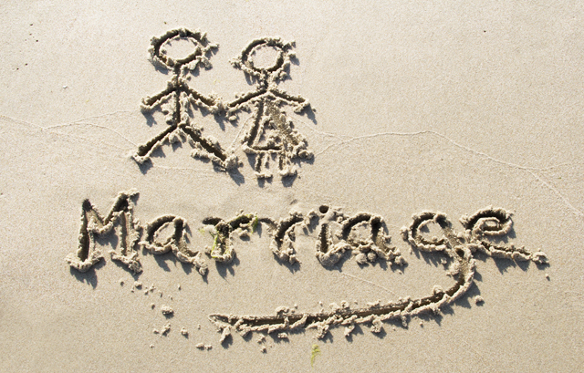 砂浜に書かれた「Marriage」の文字と男女の棒人間