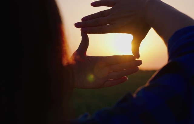 夕陽を写真に収めるイメージをする女性