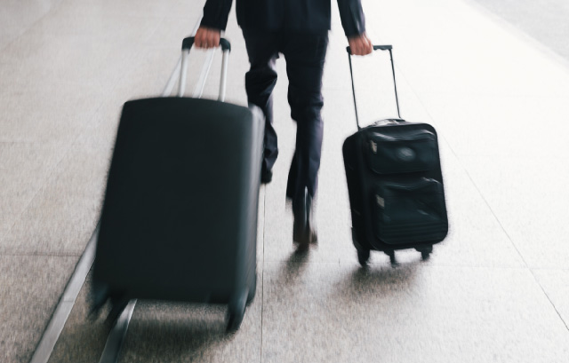 スーツケースを持って歩く男性