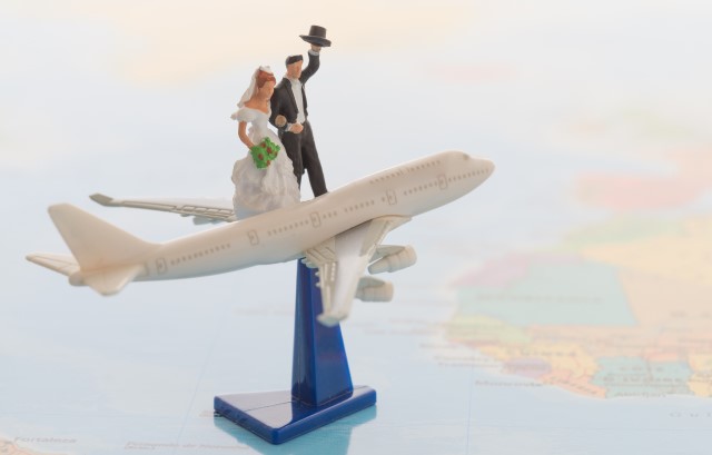 世界地図の上に置かれた飛行機と新郎新婦のミニチュア