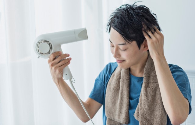 ドライヤーで髪を乾かす男性