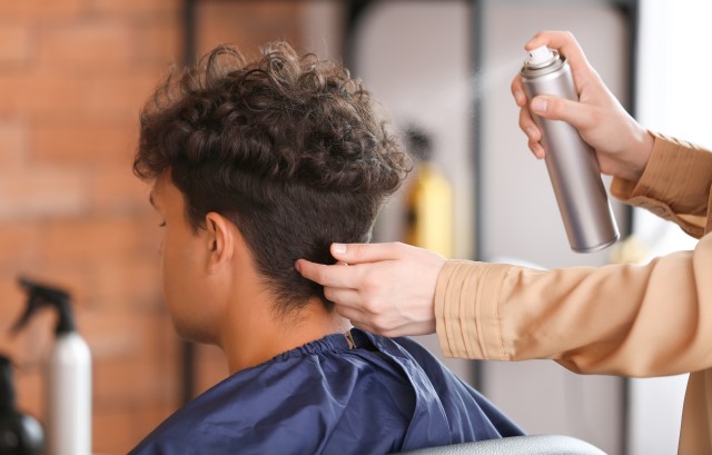 ヘアスプレーでセットする男性