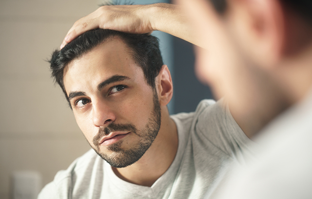 鏡で髪型をチェックする男性