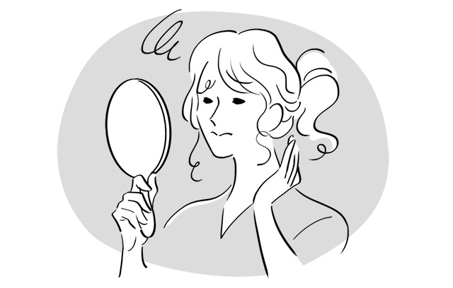 手鏡をのぞいて髪型に不満げな女性