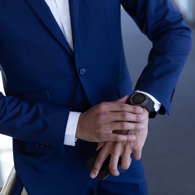 腕時計を見るスーツ姿の男性