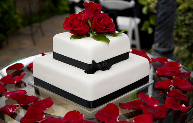 黒いリボンと赤い花が装飾されたウェディングケーキ