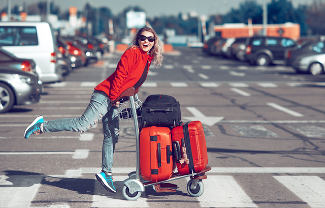 スーツケースや荷物を乗せたカートを押す女性