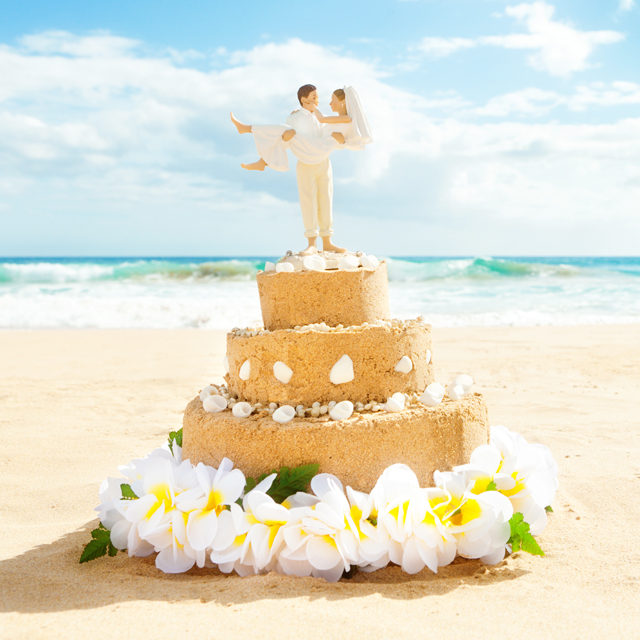 新郎新婦の人形が乗せられたビーチの砂で作ったケーキ
