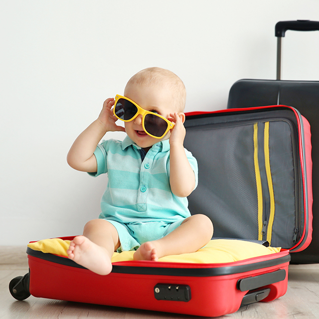 開いたスーツケースに座っている赤ちゃん