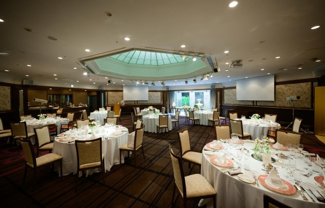 白いクロスの円卓をちらす形で配置した披露宴会場