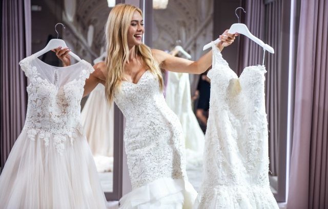 両手にウェディングドレスをもって見比べる女性