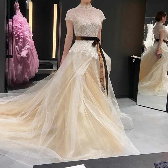 黄みがかったホワイトのドレスにブラウンのサッシュベルトを巻いている様子