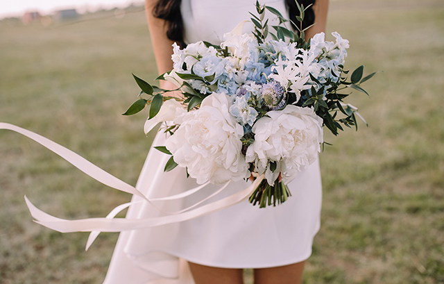 草原に立つミニ丈のウェディングドレスの花嫁