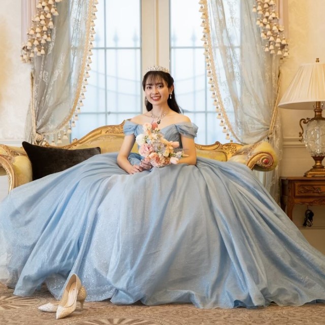 水色のプリンセスラインのドレスを着てソファーに座る花嫁