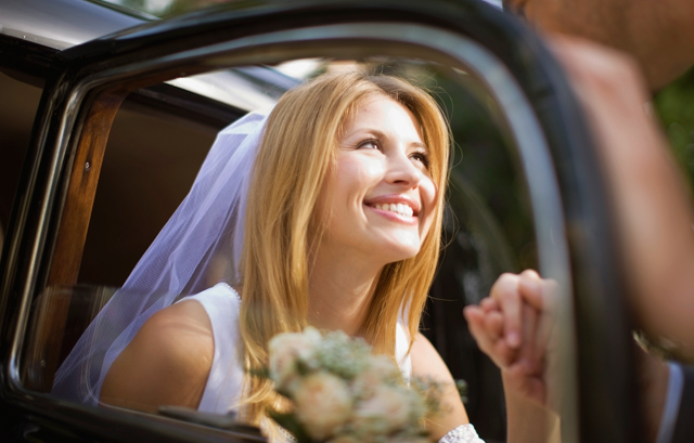 友人に手を取られ、笑顔で車から降りる花嫁