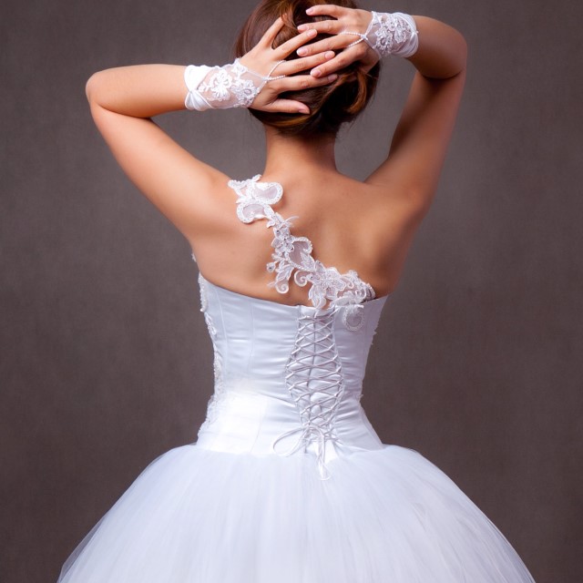 レースの肩ひもが斜めにかかるアシンメトリーなバックスタイルのウェディングドレス