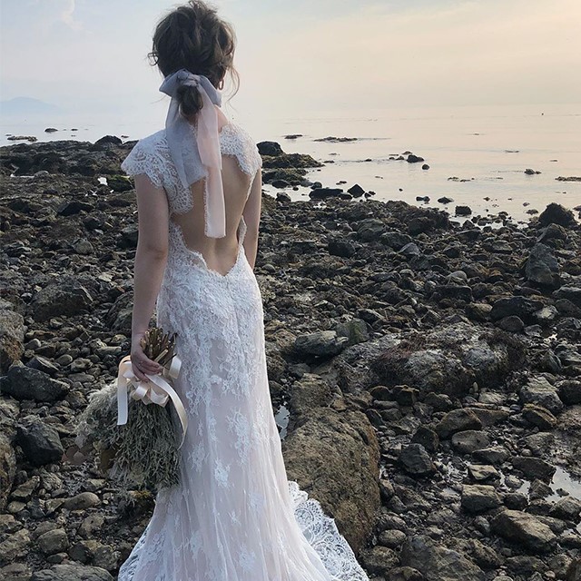 背中から腰にかけて大きく開いた、スレンダーラインのドレスを着た花嫁