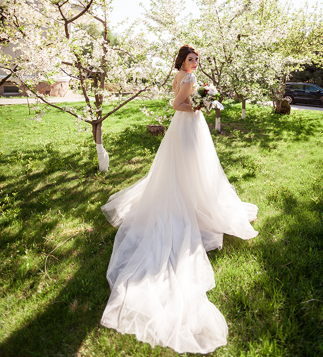 ガーデンで振り返る、ロングトレーンのドレスを着た花嫁