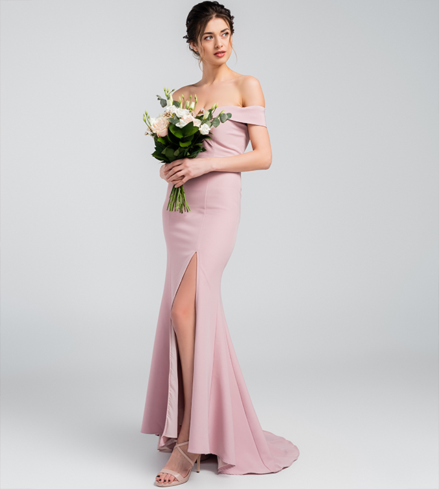 マーメイドラインのくすみピンクのドレスを着た女性