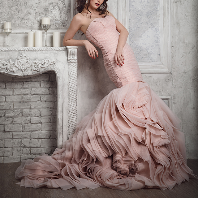 マーメイドラインの裾部分がボリューミーなピンクのドレスを着た女性