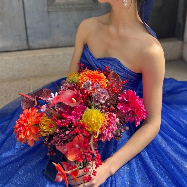 ビビッドなカラーのブーケを持ったロイヤルブルードレスの花嫁