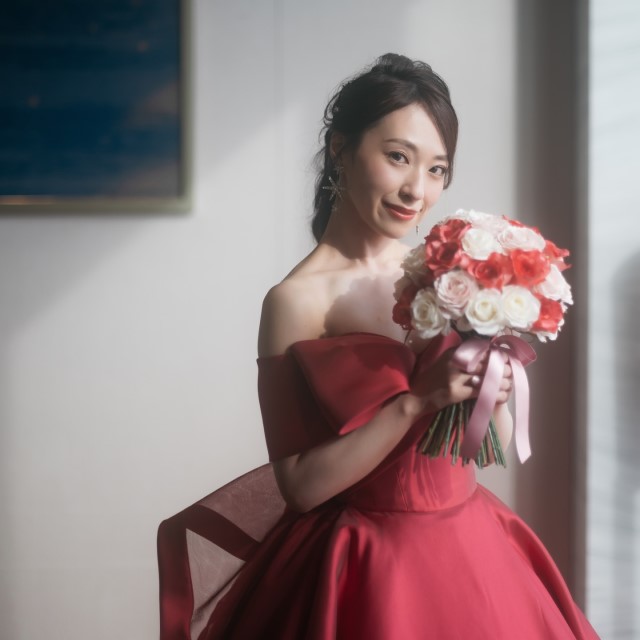 紅白ピンクのバラのブーケを持った赤いドレスの花嫁