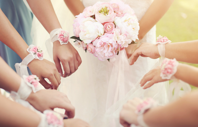 新婦が持つピンクのブーケとピンクのリストブーケをつけたゲストの腕