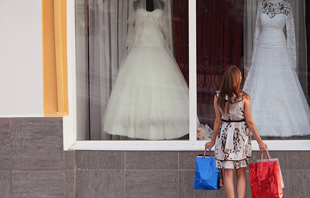 窓の向こうにあるウェディングドレスを眺める女性