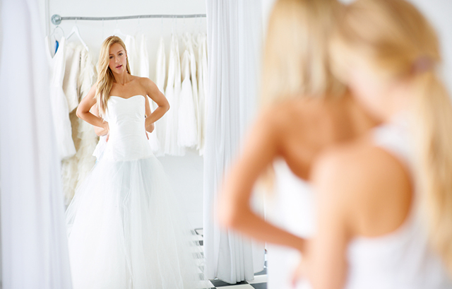 女性が試着室の鏡でウェディングドレス姿を確認している様子