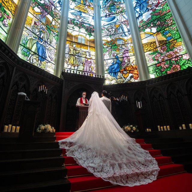 赤いカーペットの敷かれたバージンロードに広がる白いロングベール