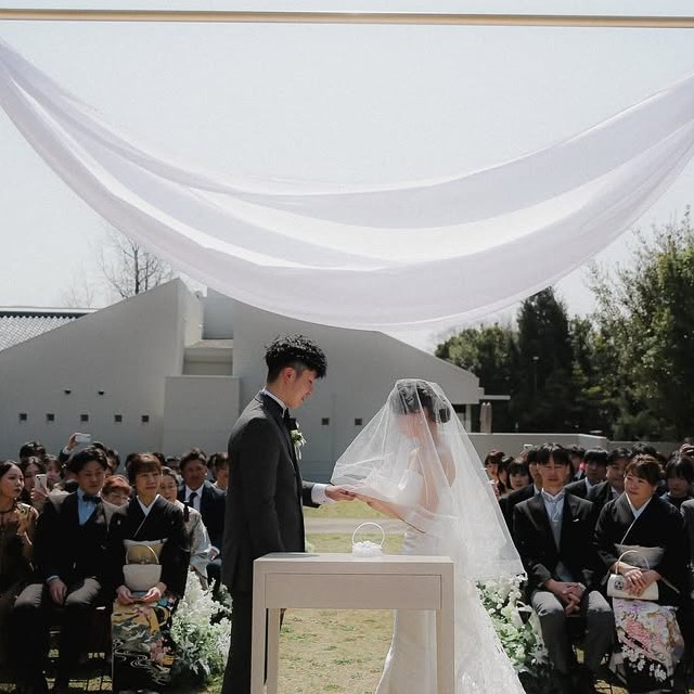 屋外の挙式でショートベールをつけた花嫁