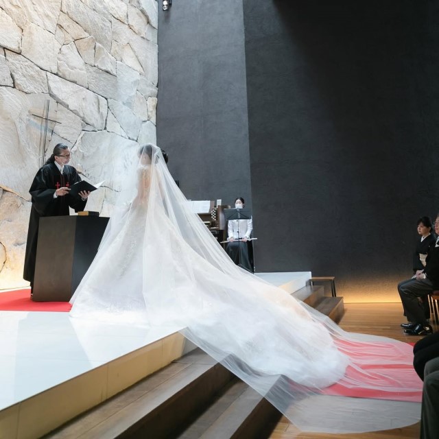 ロングベールをつけてチャペルの祭壇に立つ花嫁