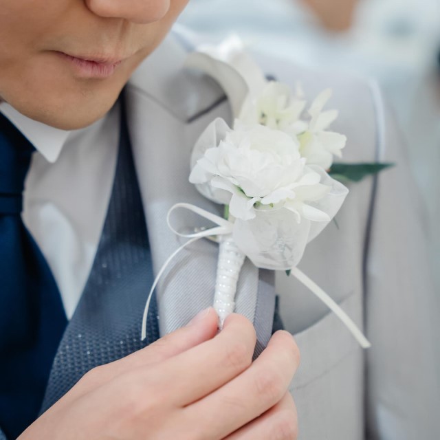 白い花のブートニアをつけた新郎