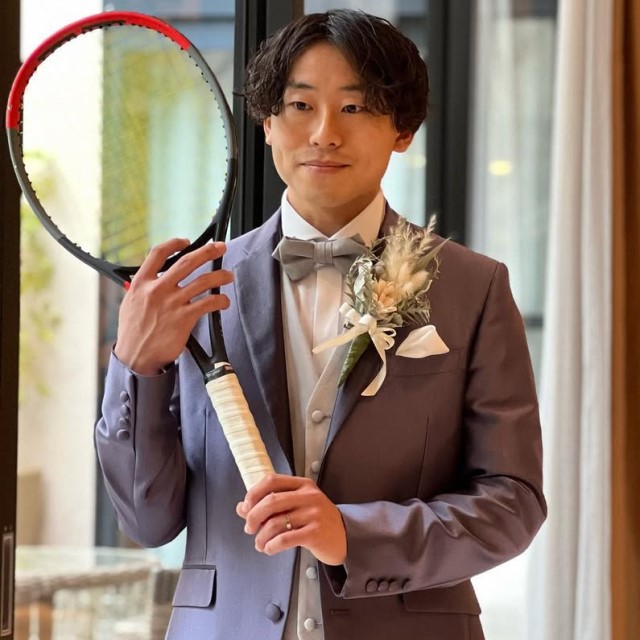 テニスラケットを持ったスーツ姿の新郎